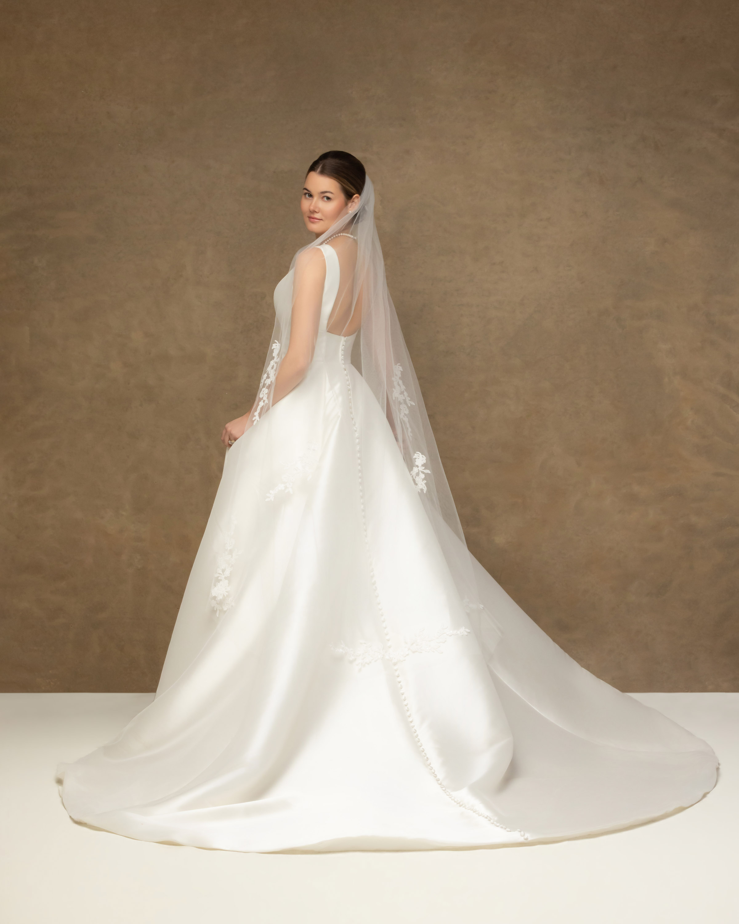Bride in her gown and veil photographed in the studio after her wedding.