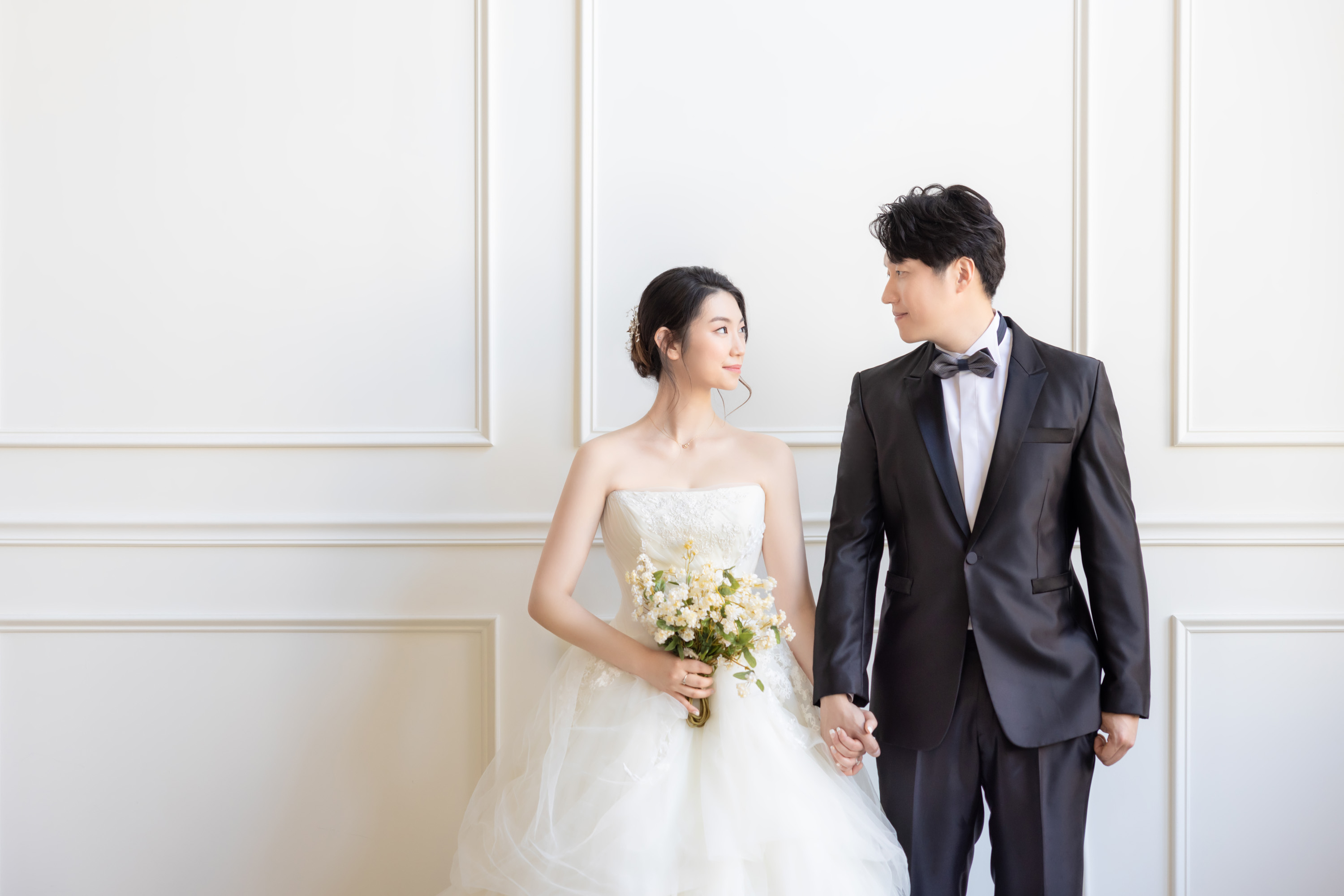 Couple in wedding clothing photographed in a bright studio.